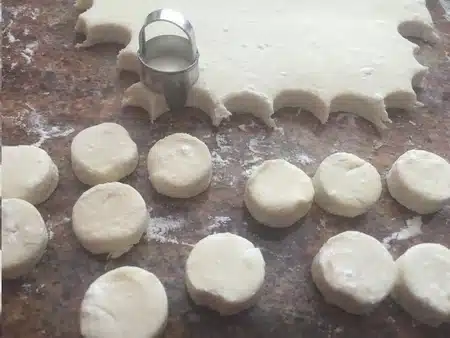 Cottage cheese scone dough and scones cut out with a round cookie cutter.