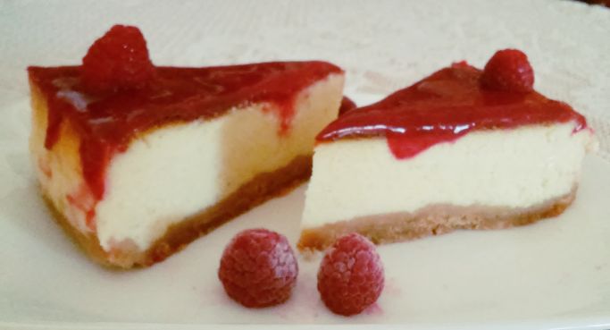 Two cheesecake slices with raspberry sauce and raspberries