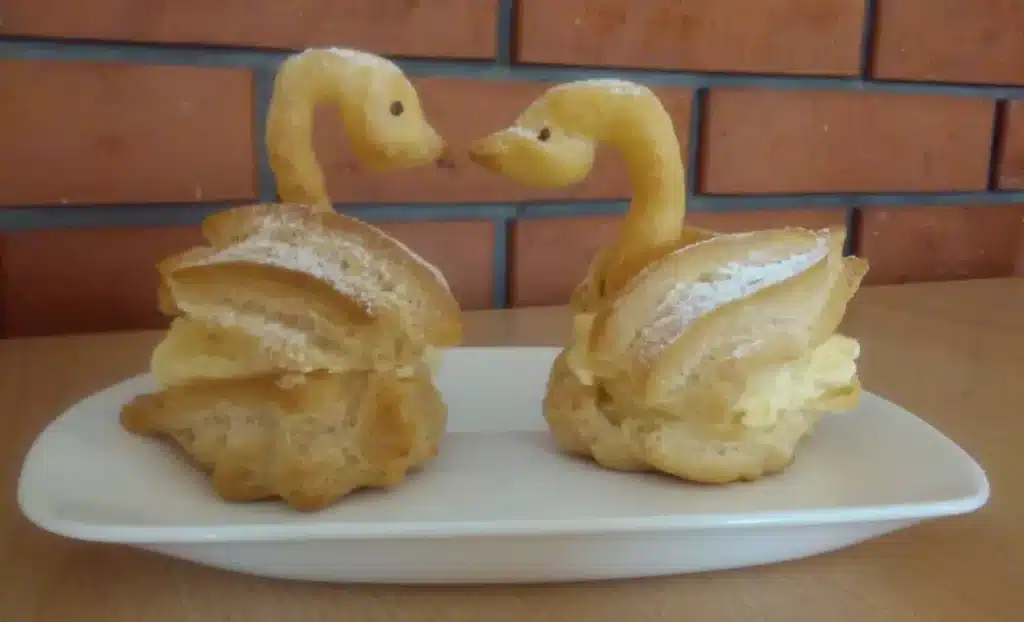 Two Choux pastry swan buns on a plate