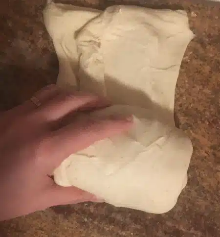 A hand rolling up bread dough.