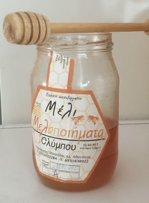 A jar of Greek orange blossom honey with a honey dipper.
