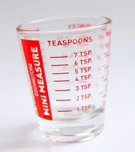 A glass measuring cup with red markings.