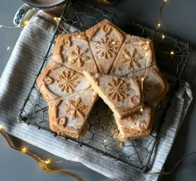 A star-shaped shortbread baked in a decorated mold, with a slice cut out and put on top.