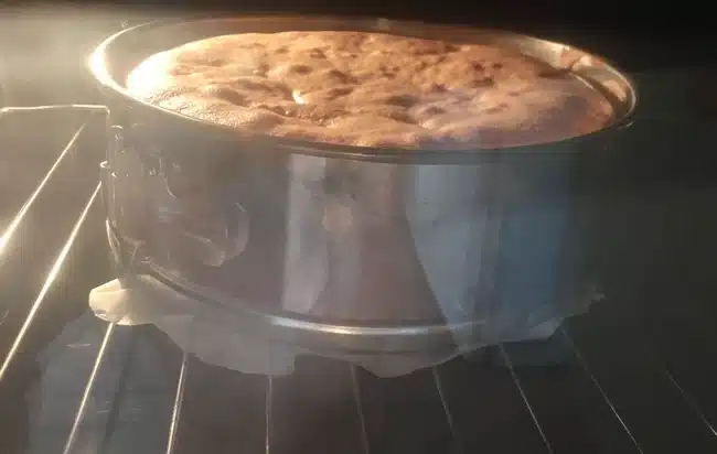 A sponge cake in a round mold inside the oven.