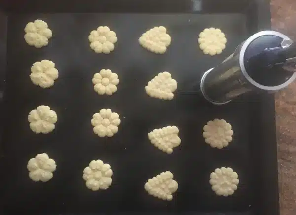 spritz cookies extruded to a baking tray, and the cookie extruder.